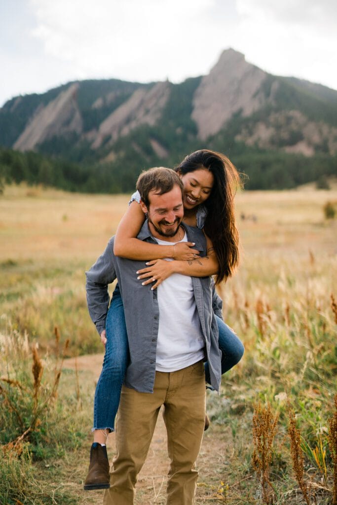 fiance giving his girlfriend a piggy back ride in boulder colorado during their Chautauqua Park Engagement Photos