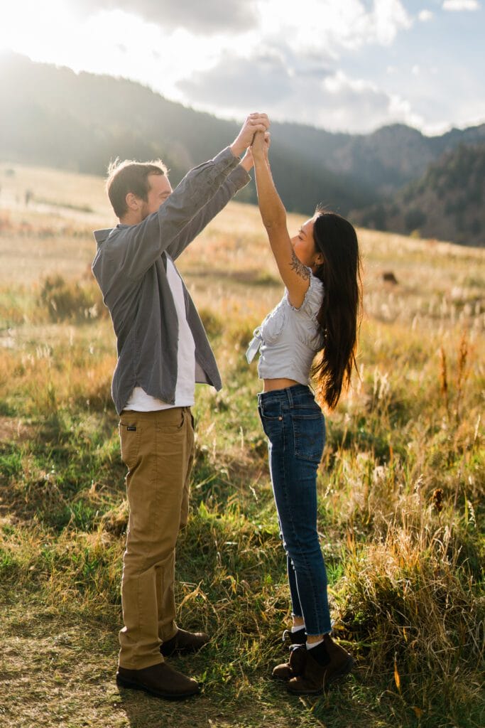 engaged couple holding hands above their heads in boulder colorado during their Chautauqua Park Engagement Photos