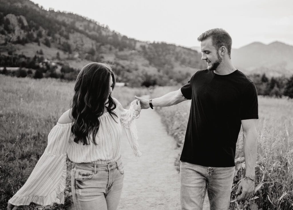 couples being playful and swinging the arms as they walk down a path together at chautauqua park  in boulder colorado