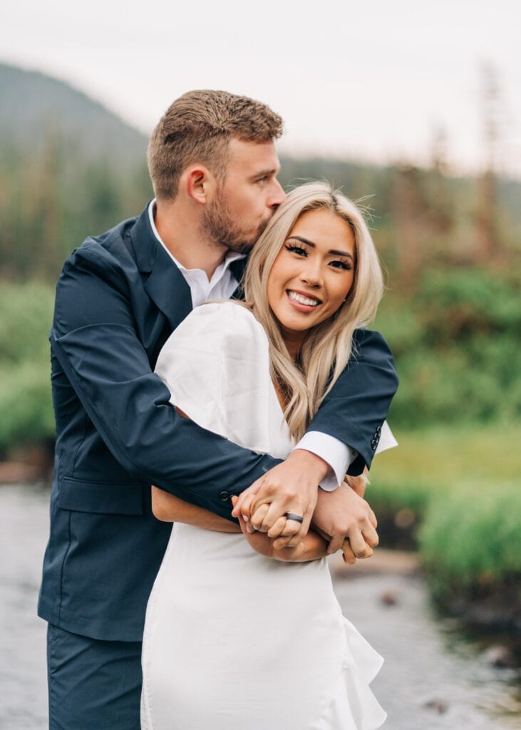 Groom hugging bride from behind while she smiles at the camera during their Colorado elopement at Brainard Lake