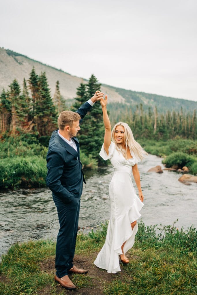 Groom kissing the bride on the head while she smiles at the camera with Lake Mitchell in the background during their Colorado Elopement at Brainard Lake Recreation Area