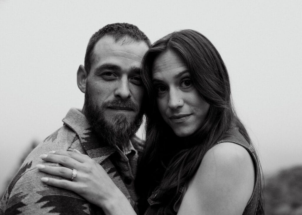 newly engaged couple with their heads together looking at the camera during their proposal in colorado