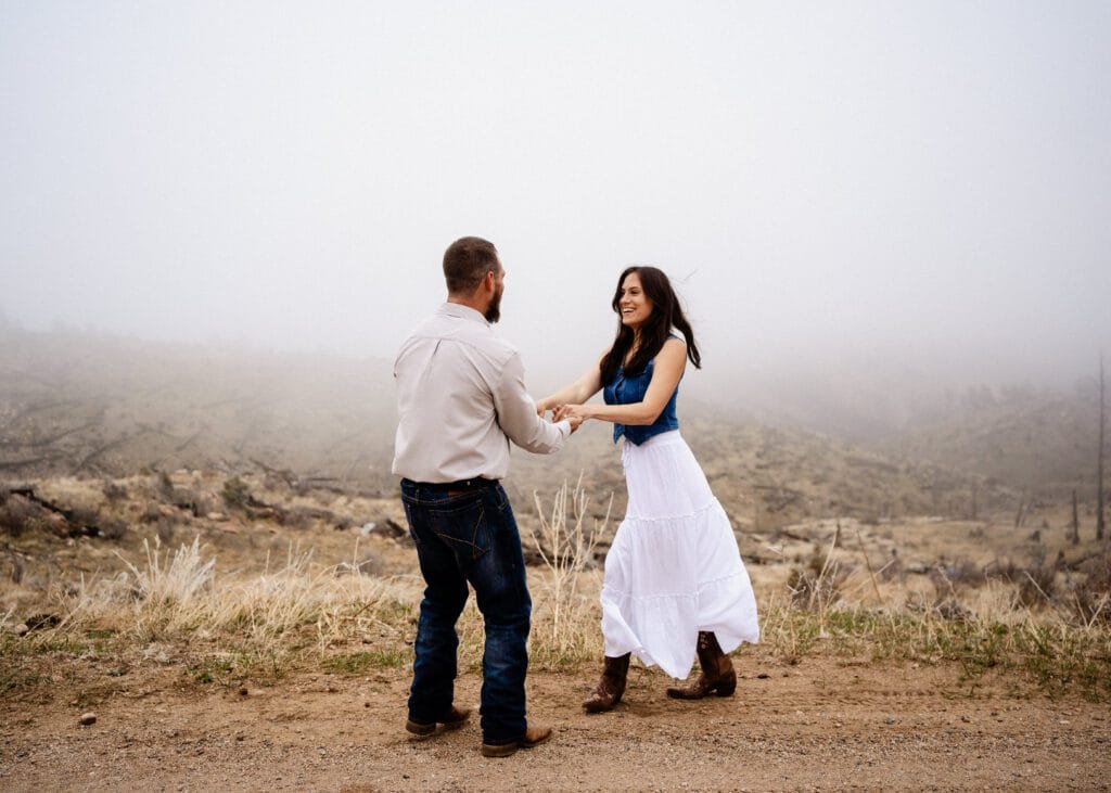 engaged couple standing on a rock kissing in the middle of field during a storm in colorado
