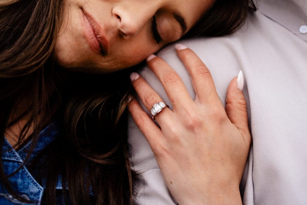 fiancee leaning on her significant other shoulder displaying her new engagement during their proposal session in colorado
