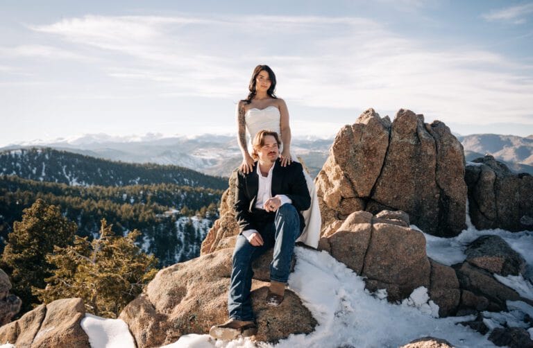 bride standing behind groom grabbing onto his shoulder as they look off into the distance during their boulder elopement in Colorado