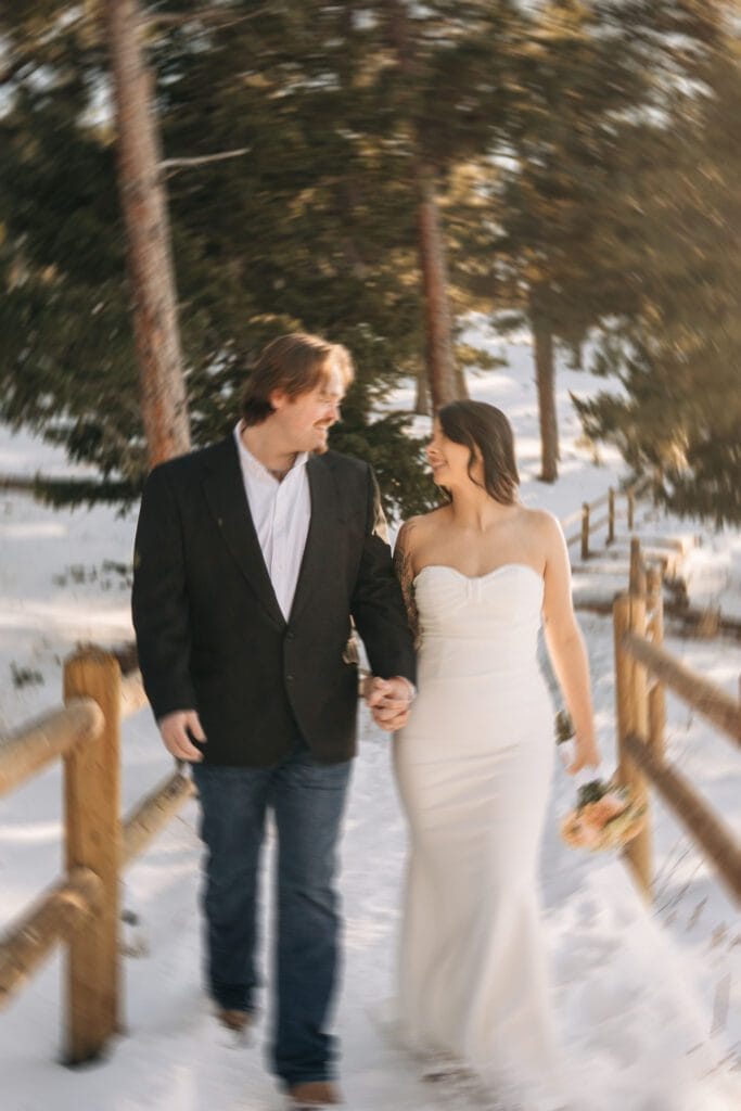 blurry image of bride and groom holding hands and walking through the forest smiling at eachother during their boulder elopement