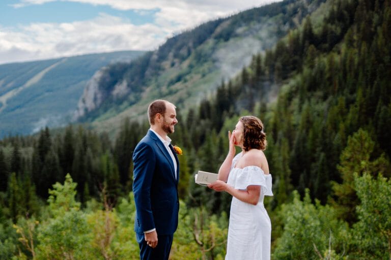 bride wiping away her tears as she reads her marriage vows to her husband during their eldora mountain colorado elopement