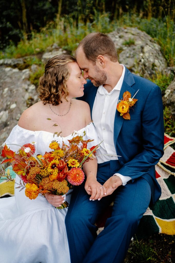bride and groom sitting on a rock outside their family cabin on eldora mountain colorado during their elopement