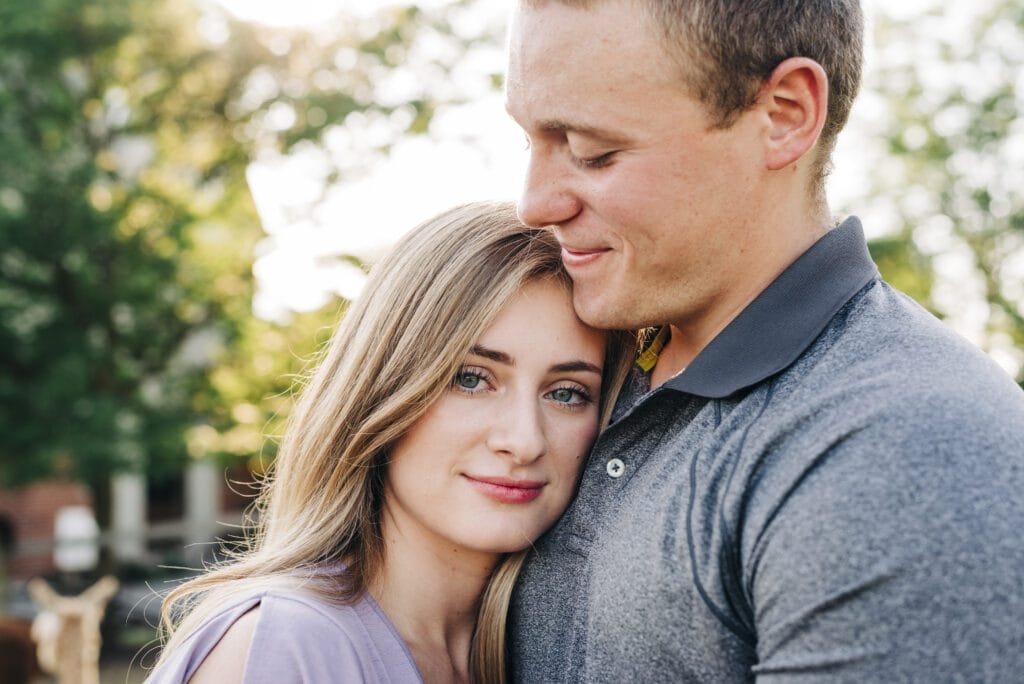 girl looking at the camera while she rests her head on her boyfriends chest during their couples photoshoot at an alpaca farm