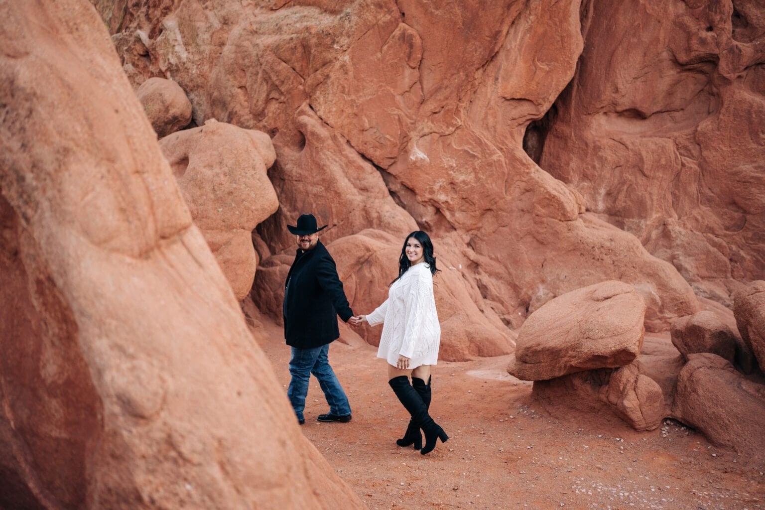 boyfriend leading her girlfriend through the park during their garden of the gods proposal photoshoot