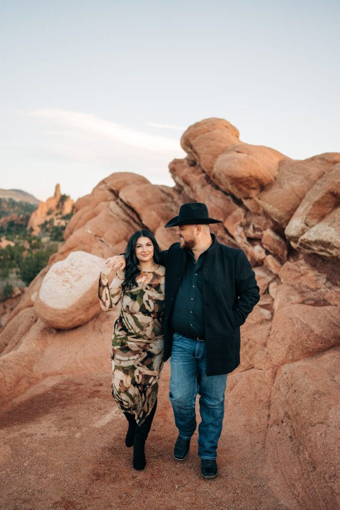 boyfriend and girlfriend walking together during their garden of the gods photoshoot with the red rocks in background