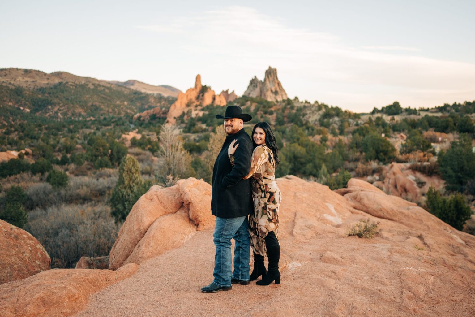 girlfriend hugging her boyfriend from behind with a big set of red rock formations behind them during their garden of the gods photoshoot