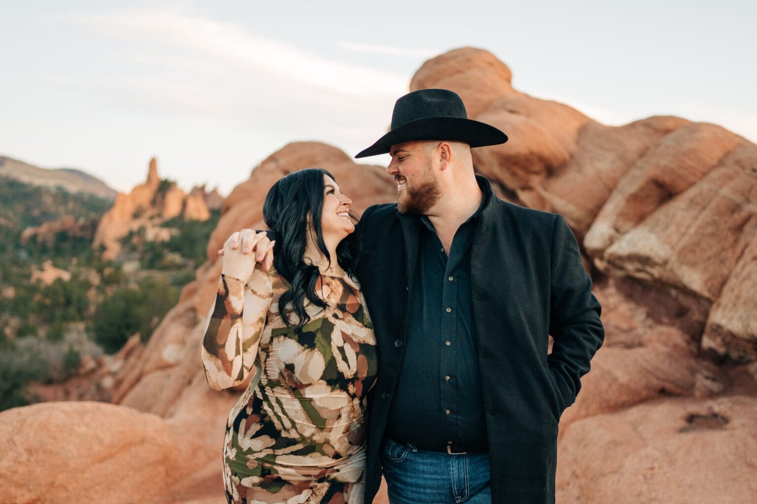 girlfriend and boyfriend walking together with arm wrapped around her shoulders during their garden of the gods photoshoot