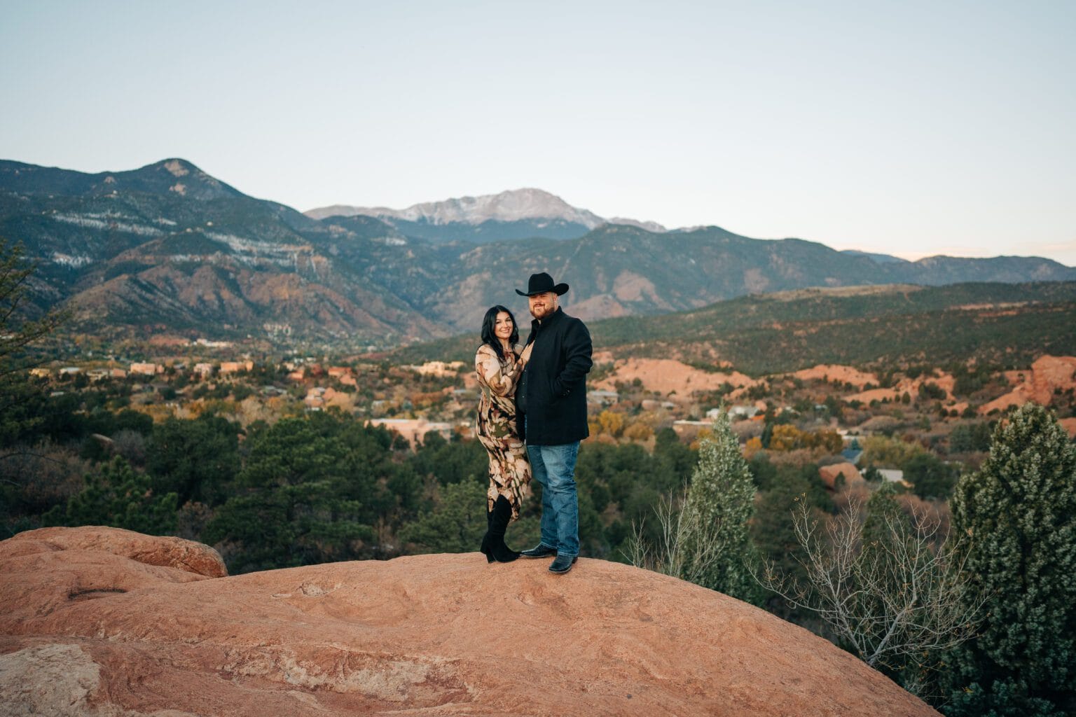 boyfriend and girlfriend smiling at the camera holding each other with pikes peak in the background