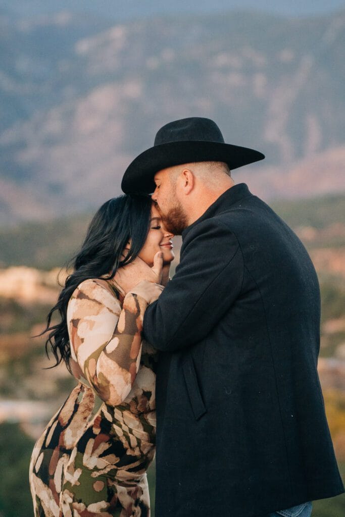 boyfriend kissing her on the forehead with pikes peak in the background during their garden of the gods photoshoot