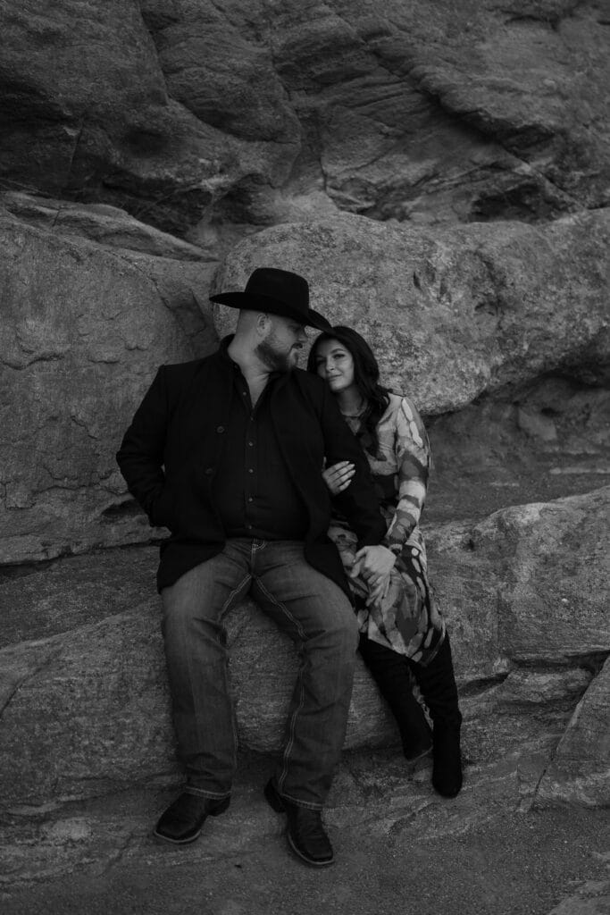 boyfriend and girlfriend sitting together on a rock during their garden of the gods photoshoot