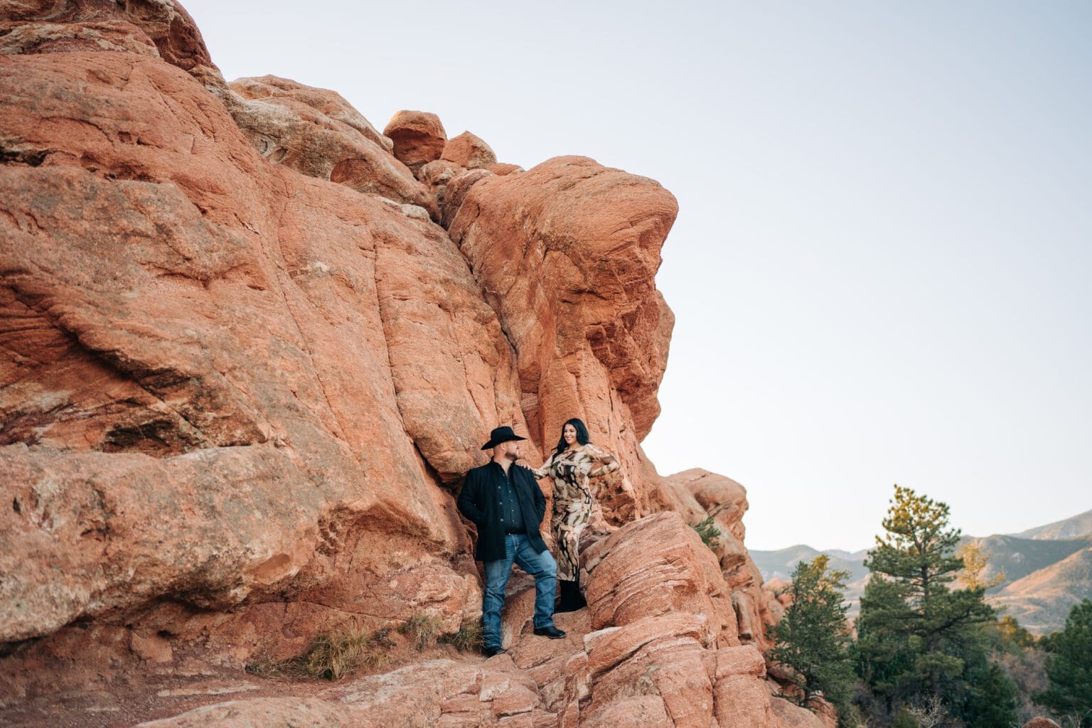 girlfriend and boyfriend standing on the red rocks looking at each other during their garden of the gods photoshoot