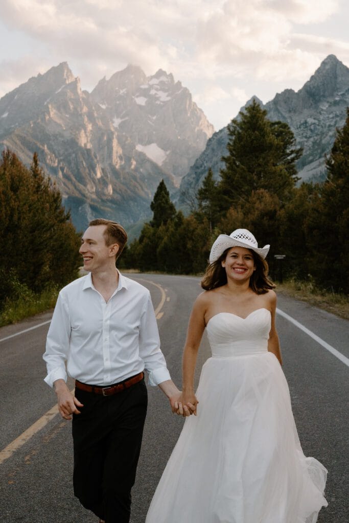 bride and groom running down the road in grand teton national park during their elopement
