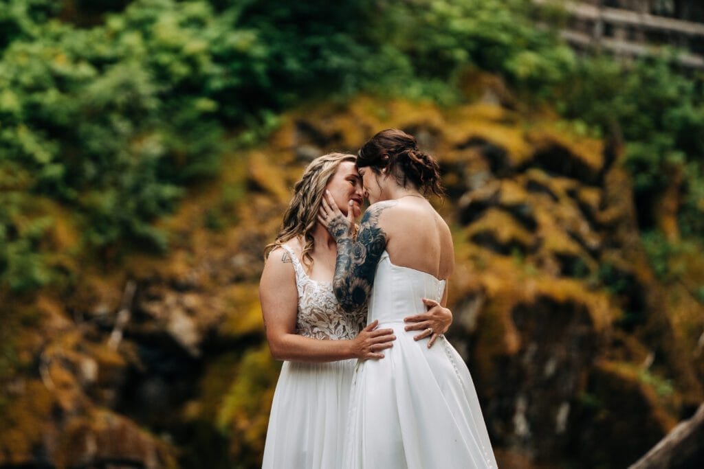 bride kissing her wife after their elopement ceremony in the forest in mt rainier national park during their washington elopement. 