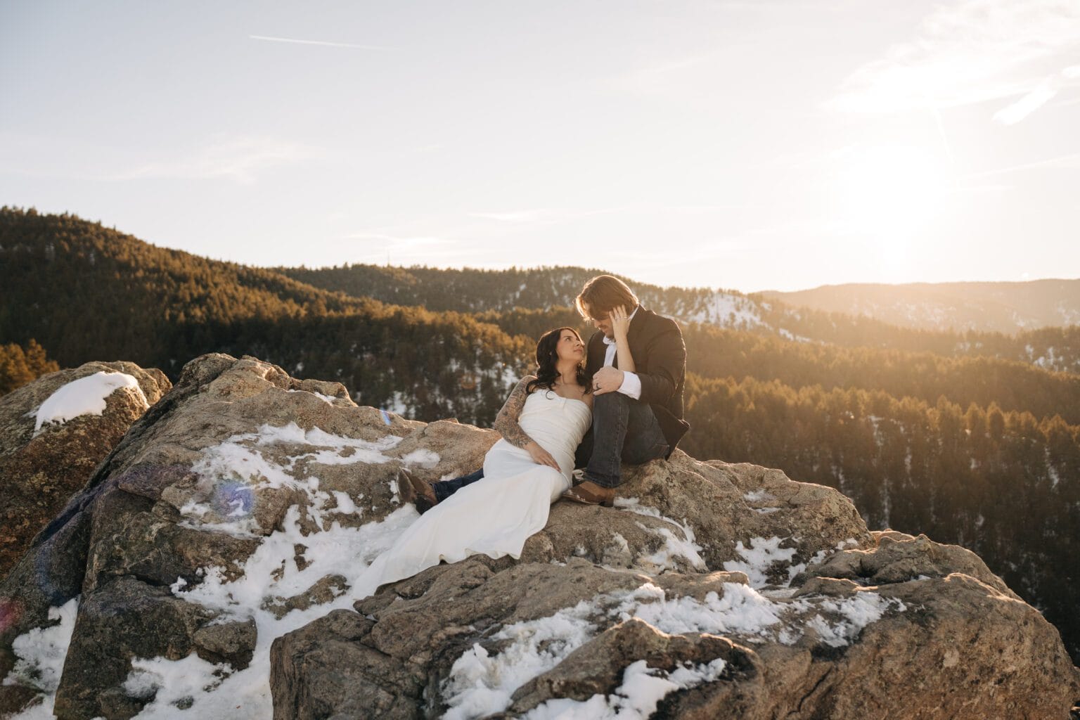 bride and groom sitting on some rocks at Lost Gulch Overlook during their sunset boulder elopement in Colorado