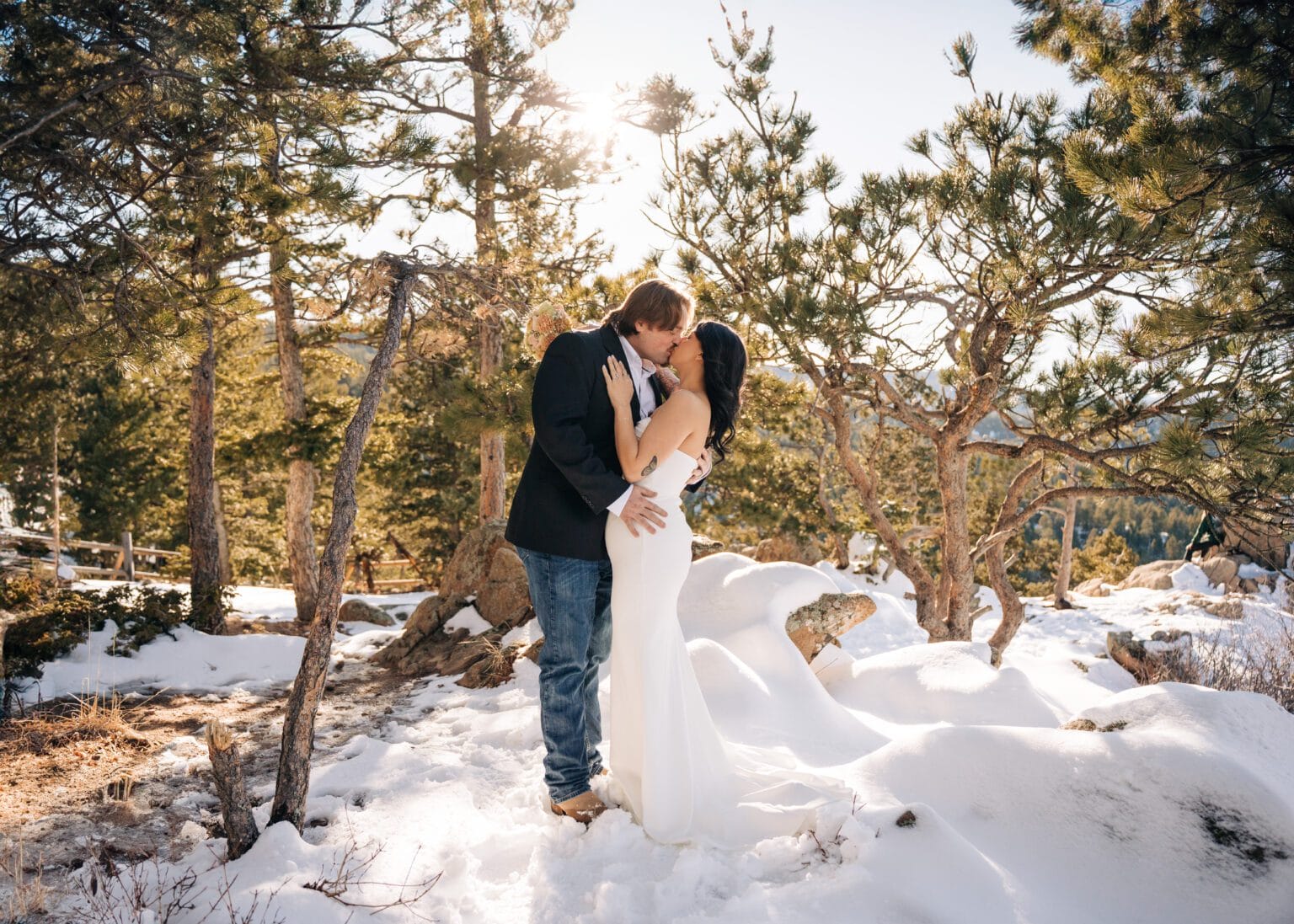 bride and groom kissing in snow covered forest during their boulder elopement in Colorado