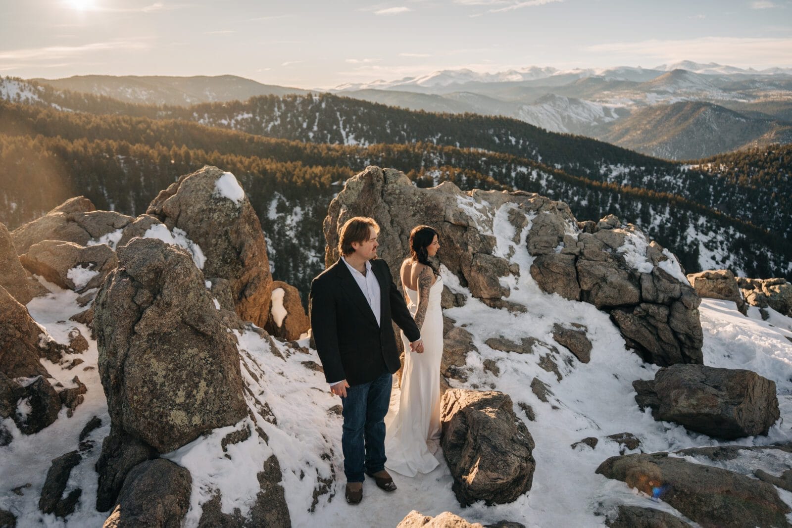 bride and groom holding hands as they watch the sunset over the mountain during their boulder elopement