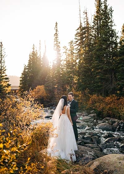 Couple in wedding attire by a scenic river