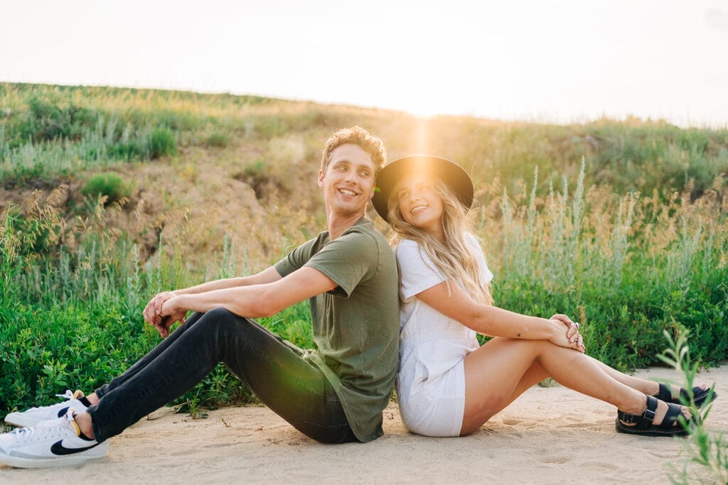 Smiling couple sitting back to back in field at the Colorado Paint Mines