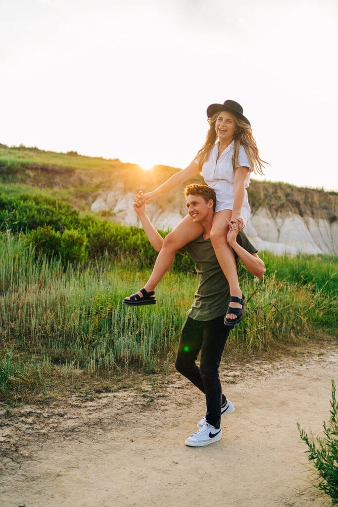 Boyfriend giving girlfriend piggyback ride at sunset during their time at the Colorado Paint Mines