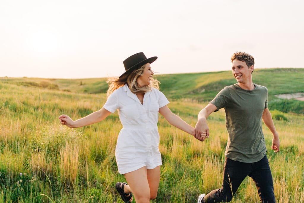 Couple holding hands, running through green field at the Colorado Paint Mines