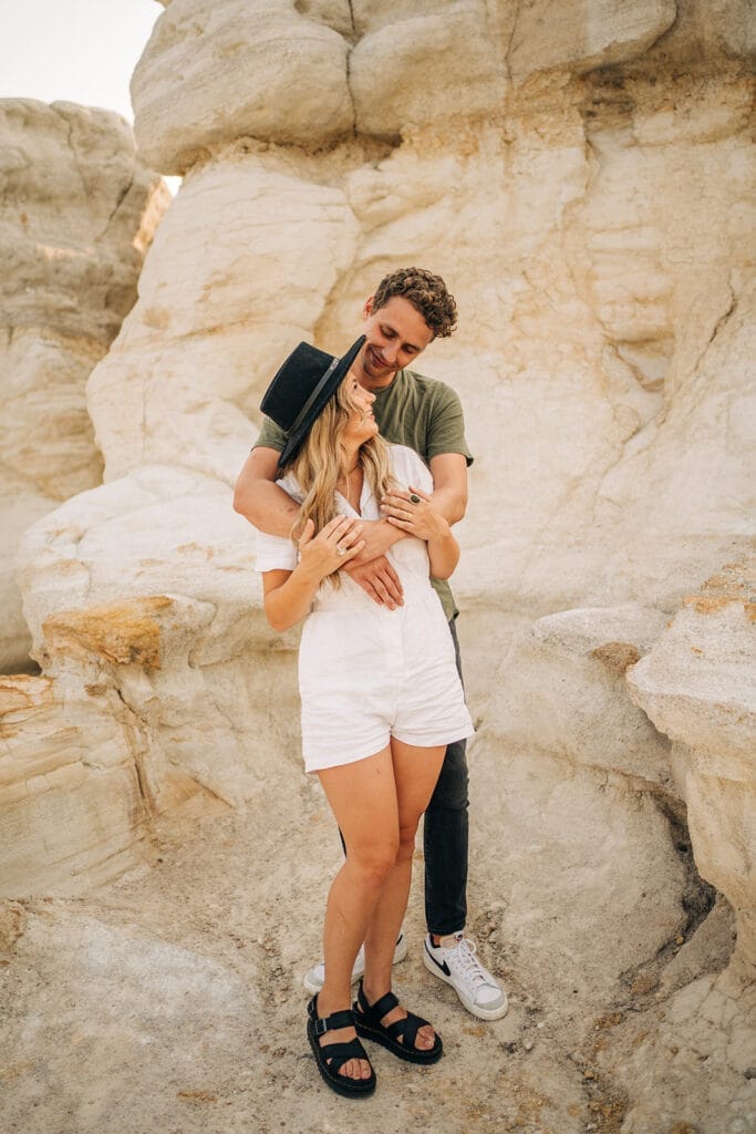Boyfriend draping arms over girlfriends shoulders during their couples photoshoot at the Colorado Paint Mines