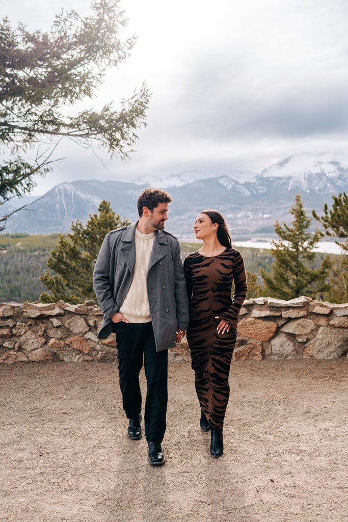 Eric and Chelsea holding hands and walking towards the camera during their engagement photos at Sapphire Point Overlook in Breckenridge, CO