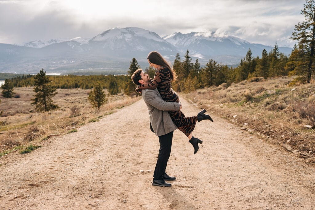 Eric picking Chelsea up as she smiles down at him after their proposal at Sapphire Point Overlook in Breckenridge, Colorado