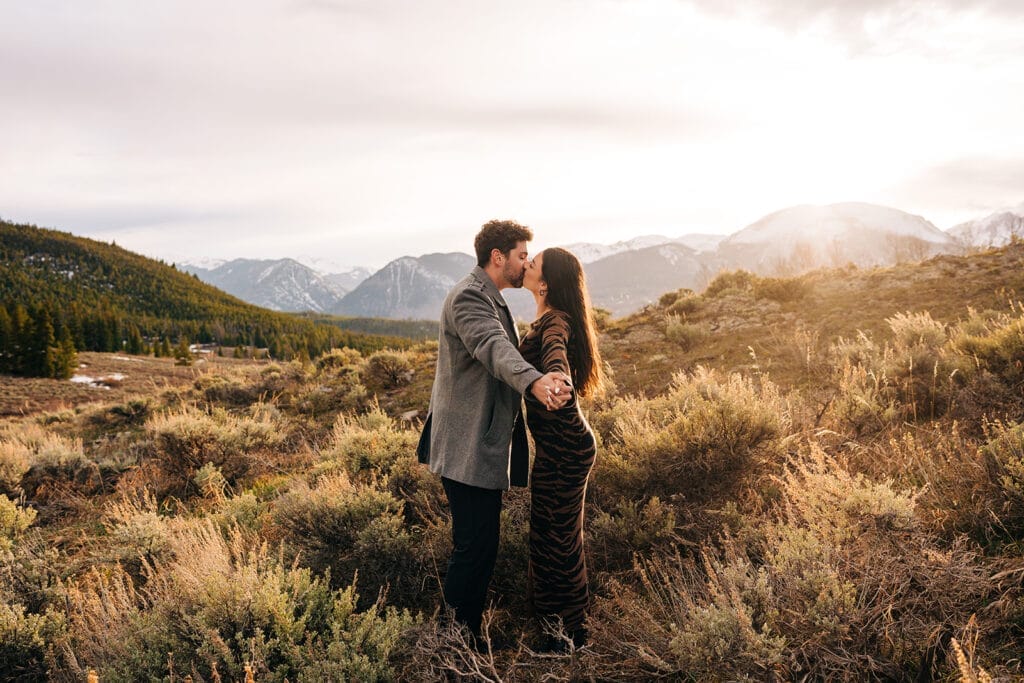 Eric and Chelsea kissing in a meadow at Sapphire Point Overlook in Breckenridge, Colorado during sunset