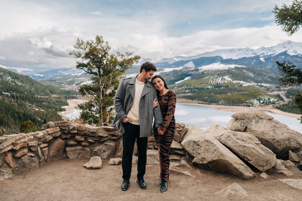 Newly engaged couple holding hands as girlfriend rests her head on his shoulder at Sapphire Point Overlook in Breckenridge, CO