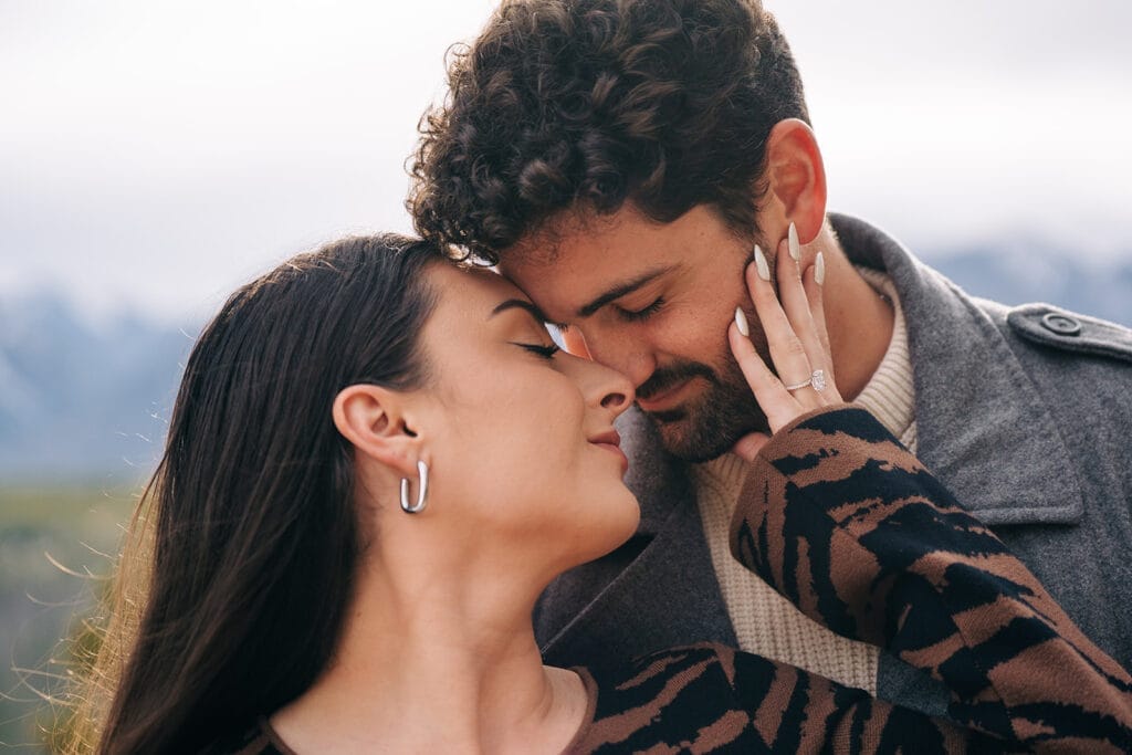 Chelsesa and Eric nose to nose as she grabs his face during their engagement photos at Sapphire Point Overlook in Breckenridge, CO