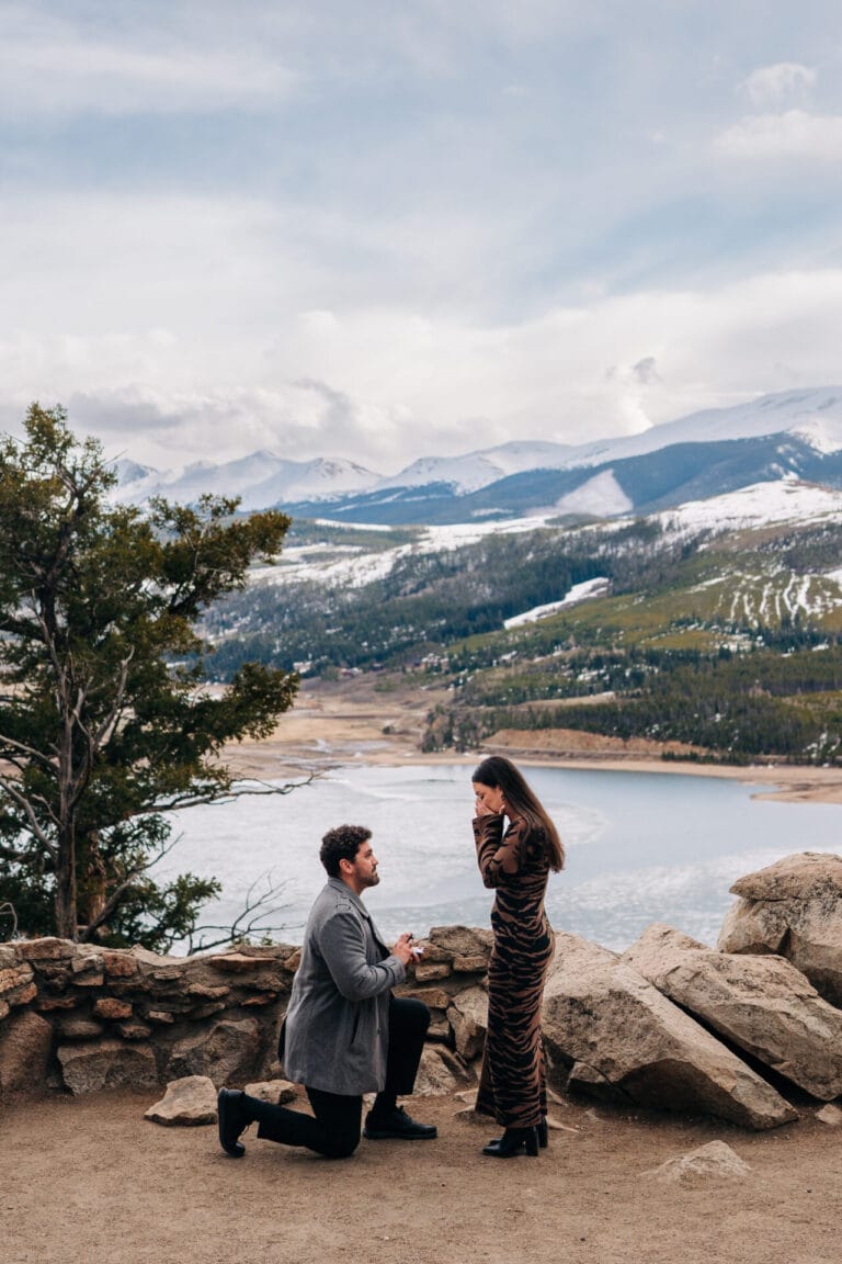 Eric down on his knee proposing to his girlfriend Chelsea at Sapphire Point Overlook in Breckenridge, Colorado.